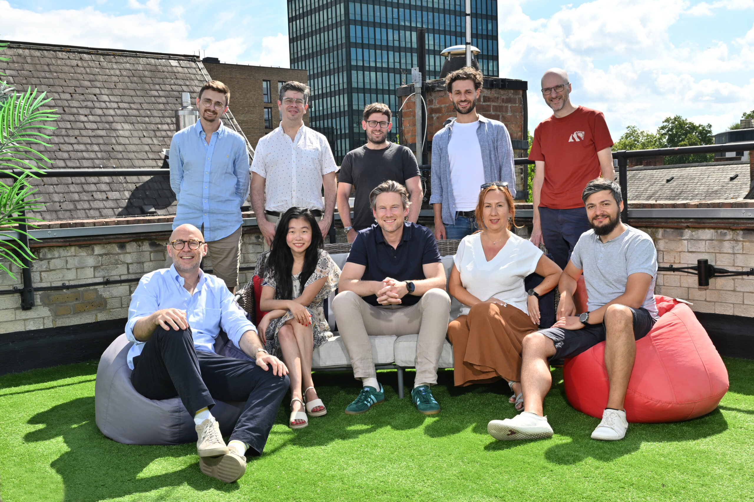 Group photo of the Phoebe team sitting and standing together outdoors in front of a brick building and greenery.